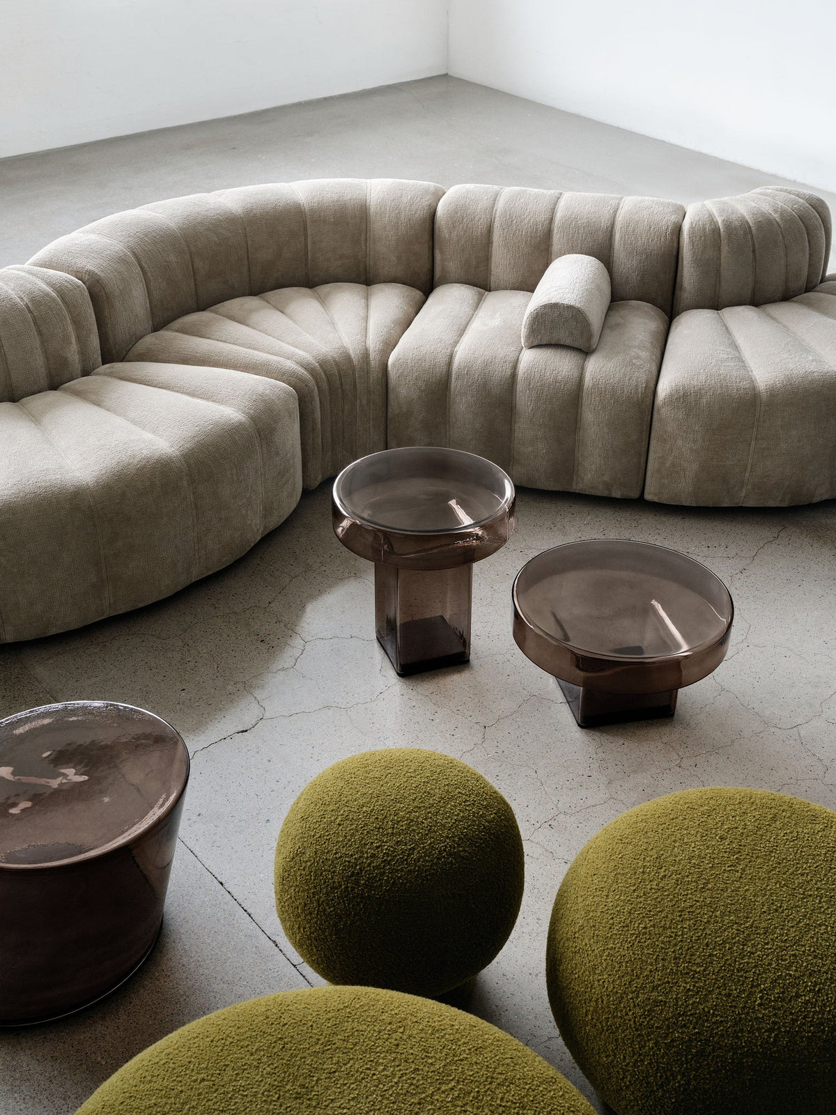 NORR11 Studio sofa with glass tables and green poufs.