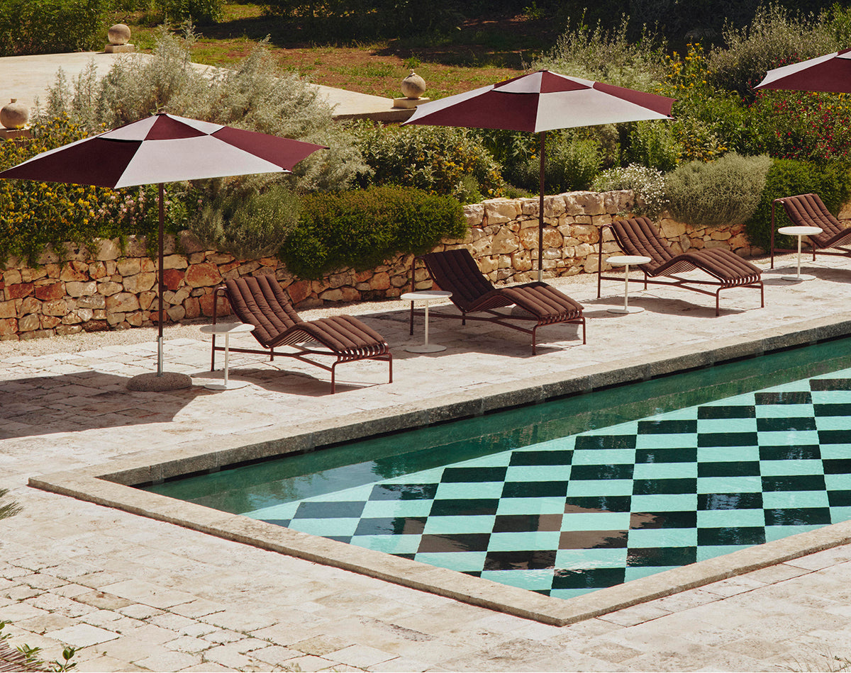 HAY Palissade outdoor furniture beside a swimming pool and planted terrace.