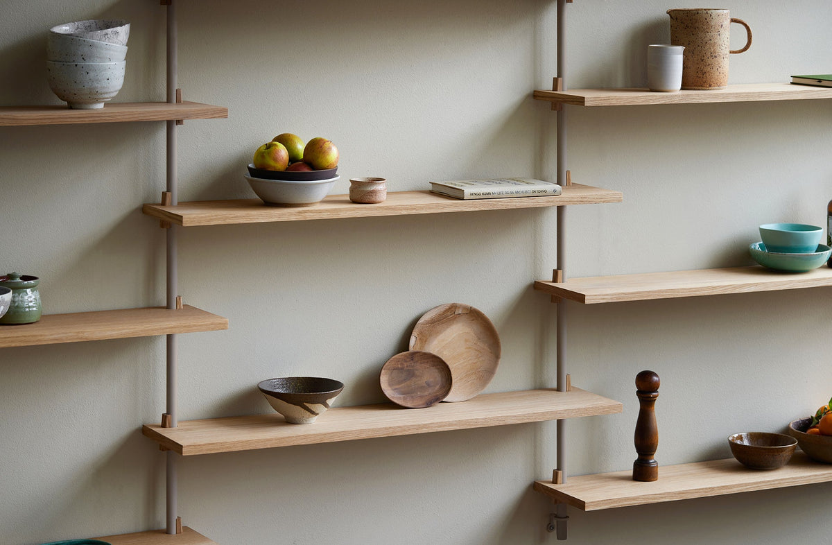 MOEBE wall shelving in oak and warm grey in a light interior.