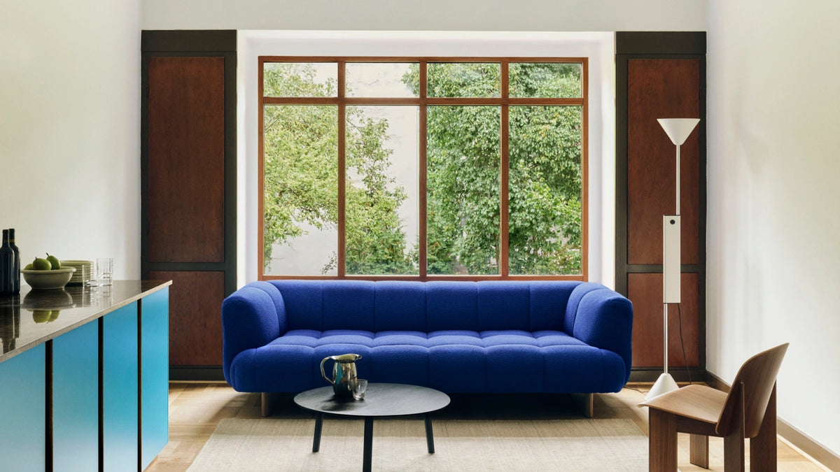 Blue HAY sofa with tables and lighting in a bright living room.