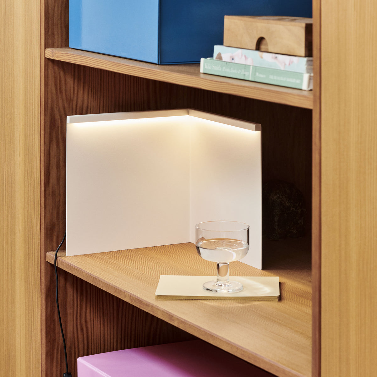 HAY LBM Corner Table Lamp in cream white illuminating a wooden shelving corner