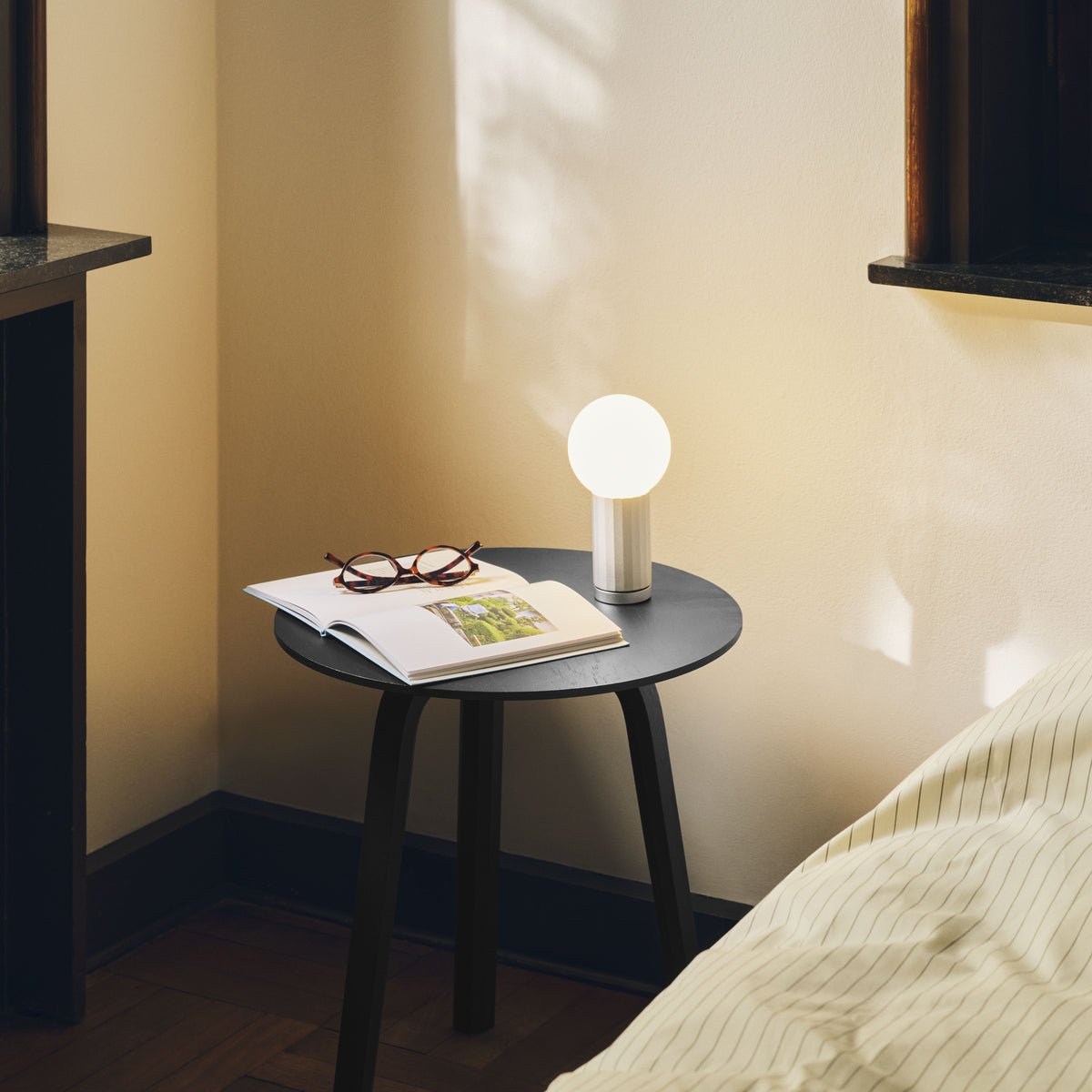 HAY Turn On Table Lamp in aluminium on a black Bella side table beside a bed