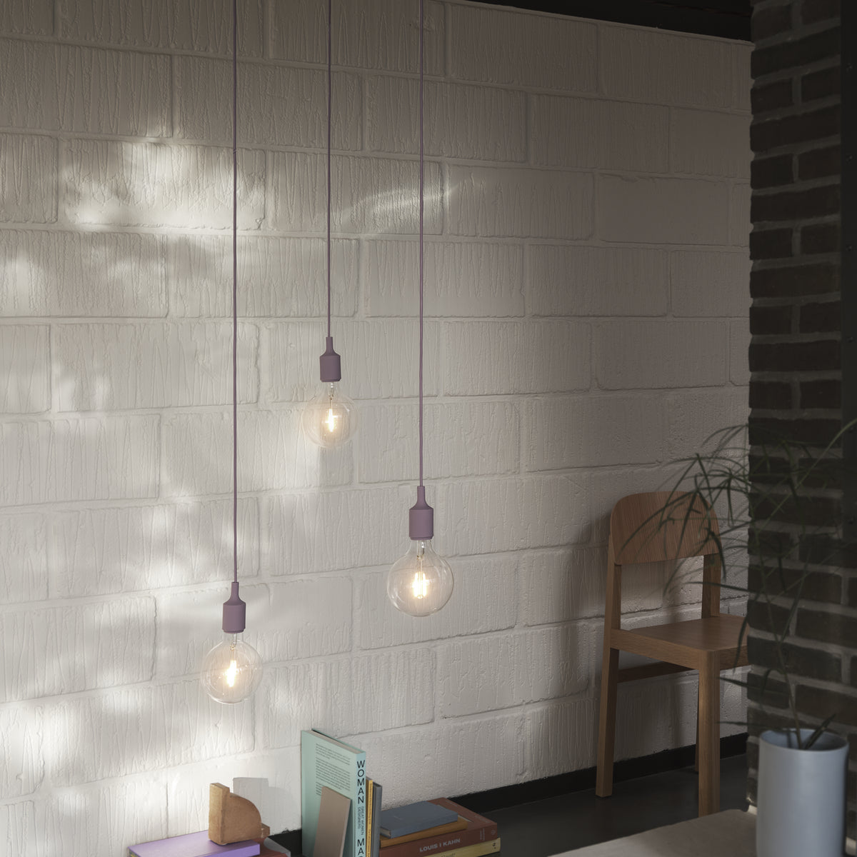 Muuto E27 family context: dusty lilac pendant lamps above a table, showing individual lamps rather than a canopy cluster