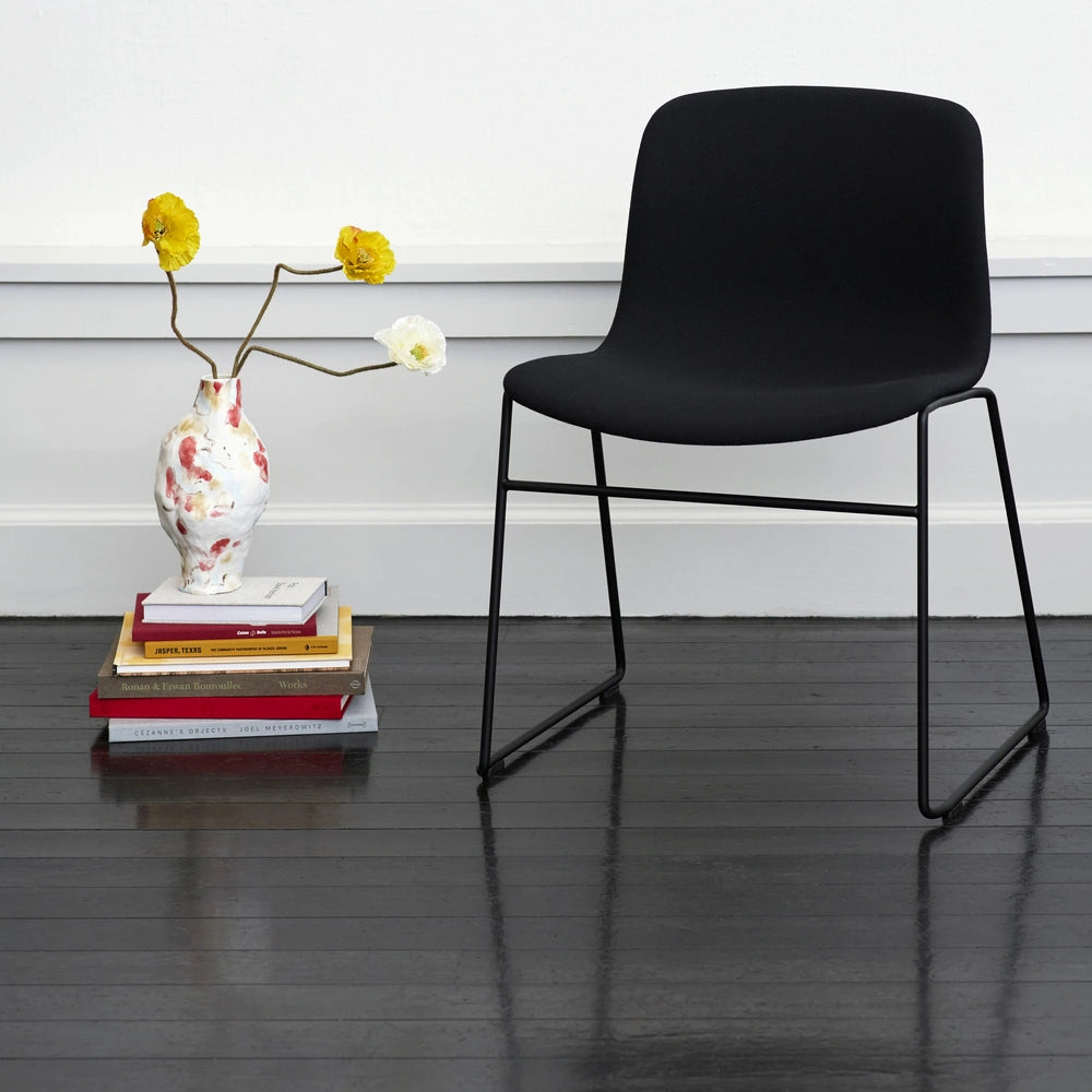 Family context: HAY AAC 09 fully upholstered sled-base chair with books and a vase
