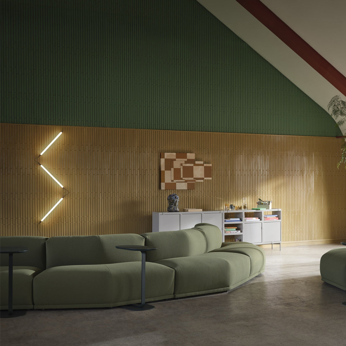 Muuto Fine Wall/Ceiling family installation with three light profiles in a vertical zigzag above a green sofa. Family/layout context; the pictured arrangement differs from the standard product configuration.