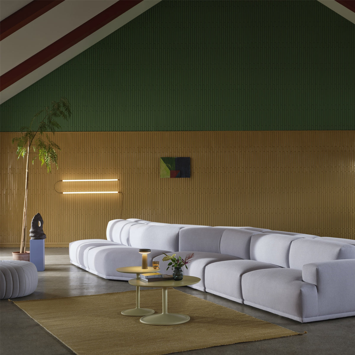Muuto Fine Wall/Ceiling family installation with two parallel horizontal light profiles above a pale sofa. Family/layout context; the pictured arrangement differs from the standard product configuration.