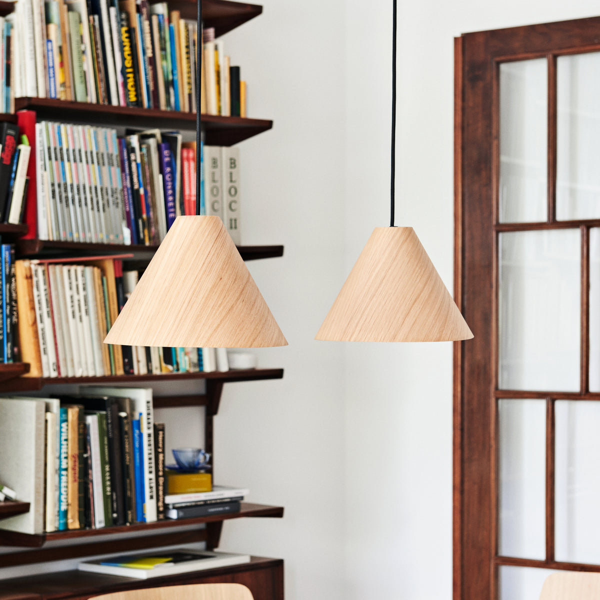 HAY 30 Degrees medium oak shades above a dining table beside bookshelves; cord sets sold separately