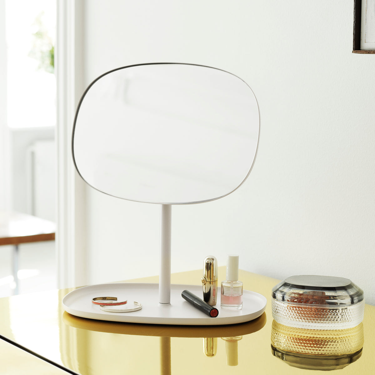 Normann Copenhagen Flip mirror on a surface beside daily objects